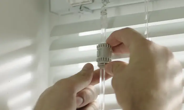 Hands installing SwitchBot Blind Tilt onto an existing horizontal blind wand