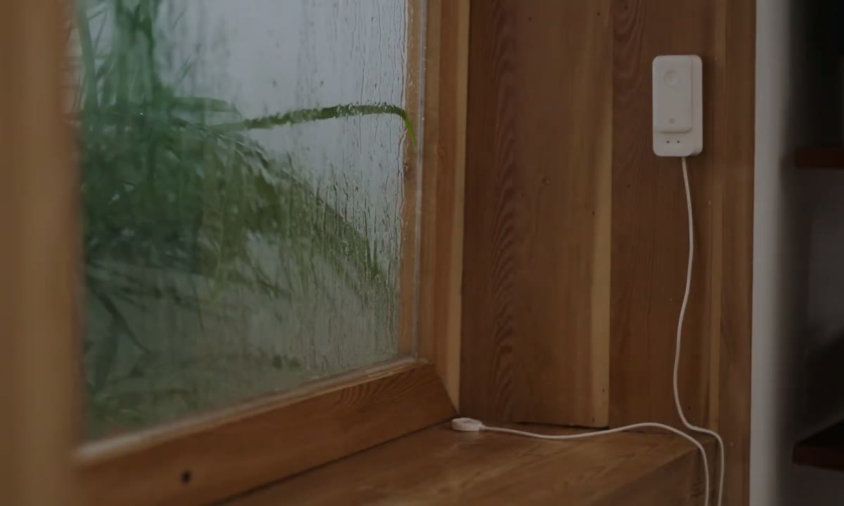 Water Leak Detector and sensor cable placed beside a rainy window