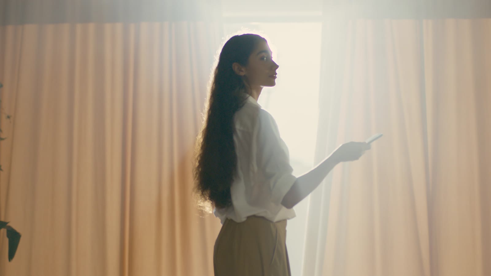 Person using SwitchBot curtain control in a bright condo-style room